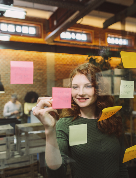Woman writing on Post it note